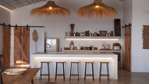 Une cuisine moderne avec un îlot central, des tabourets de bar et des luminaires suspendus en forme de toits de chaume.