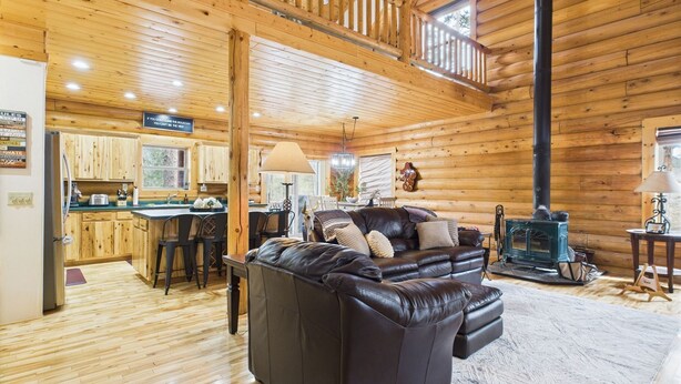 Un intérieur de cabine spacieux, avec un plancher en bois, un canapé en cuir noir, un coin repas et une cuisine.