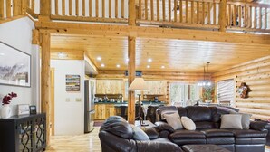Un intérieur de cabine spacieux, avec un grand plafond en bois, un coin salon confortable doté de canapés en cuir, une table à manger et un espace cuisine.