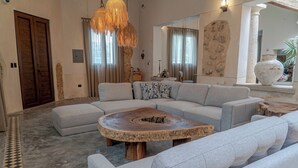 Un salon moderne avec un canapé d’angle, une table basse ronde et un grand miroir.