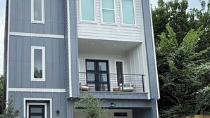 Un immeuble résidentiel à deux étages, doté d’un garage, d’un petit jardin devant et d’une clôture en bois à l’arrière.