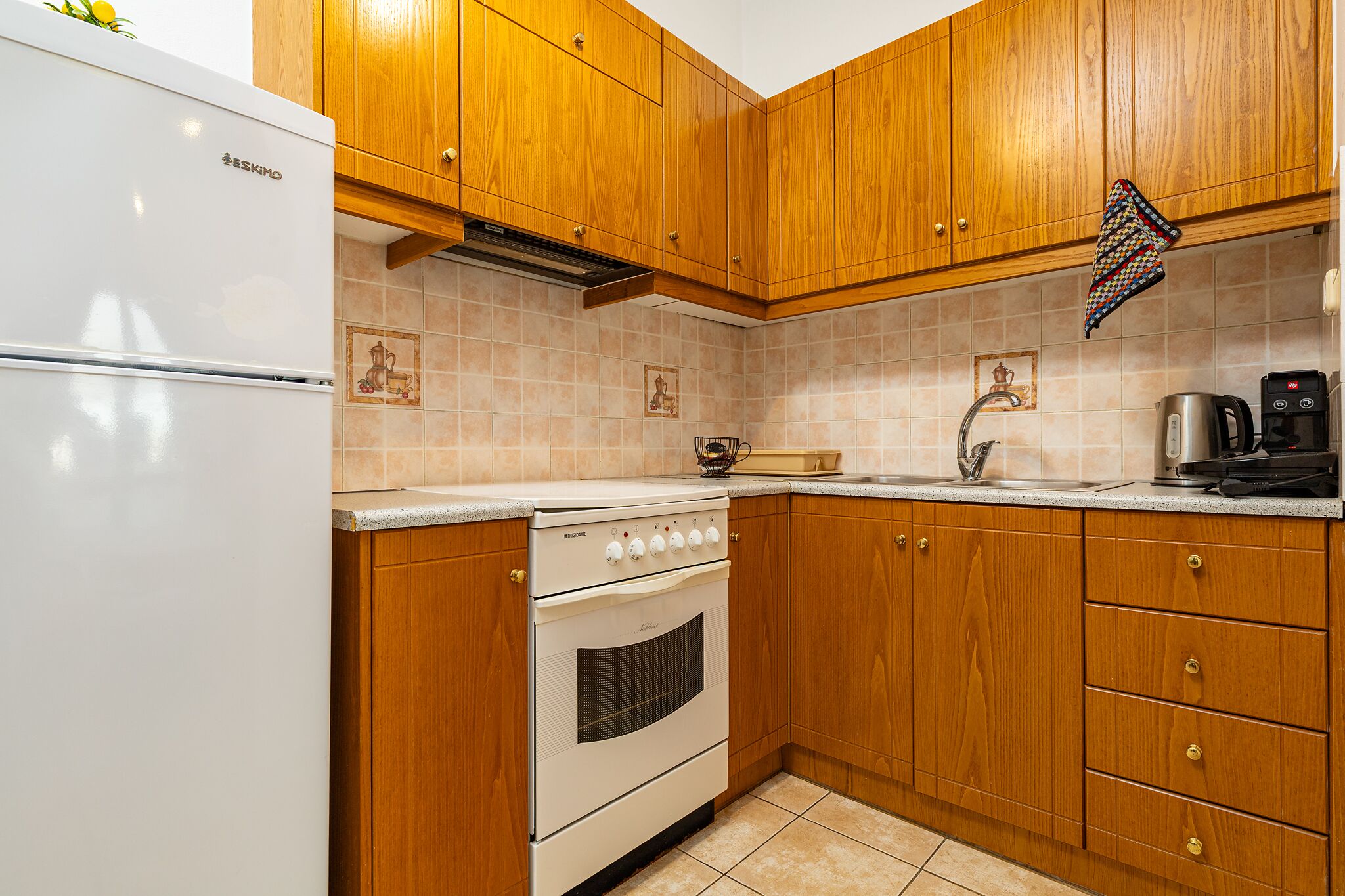 A kitchen with wooden cabinets, a white stove, and a white refrigerator.