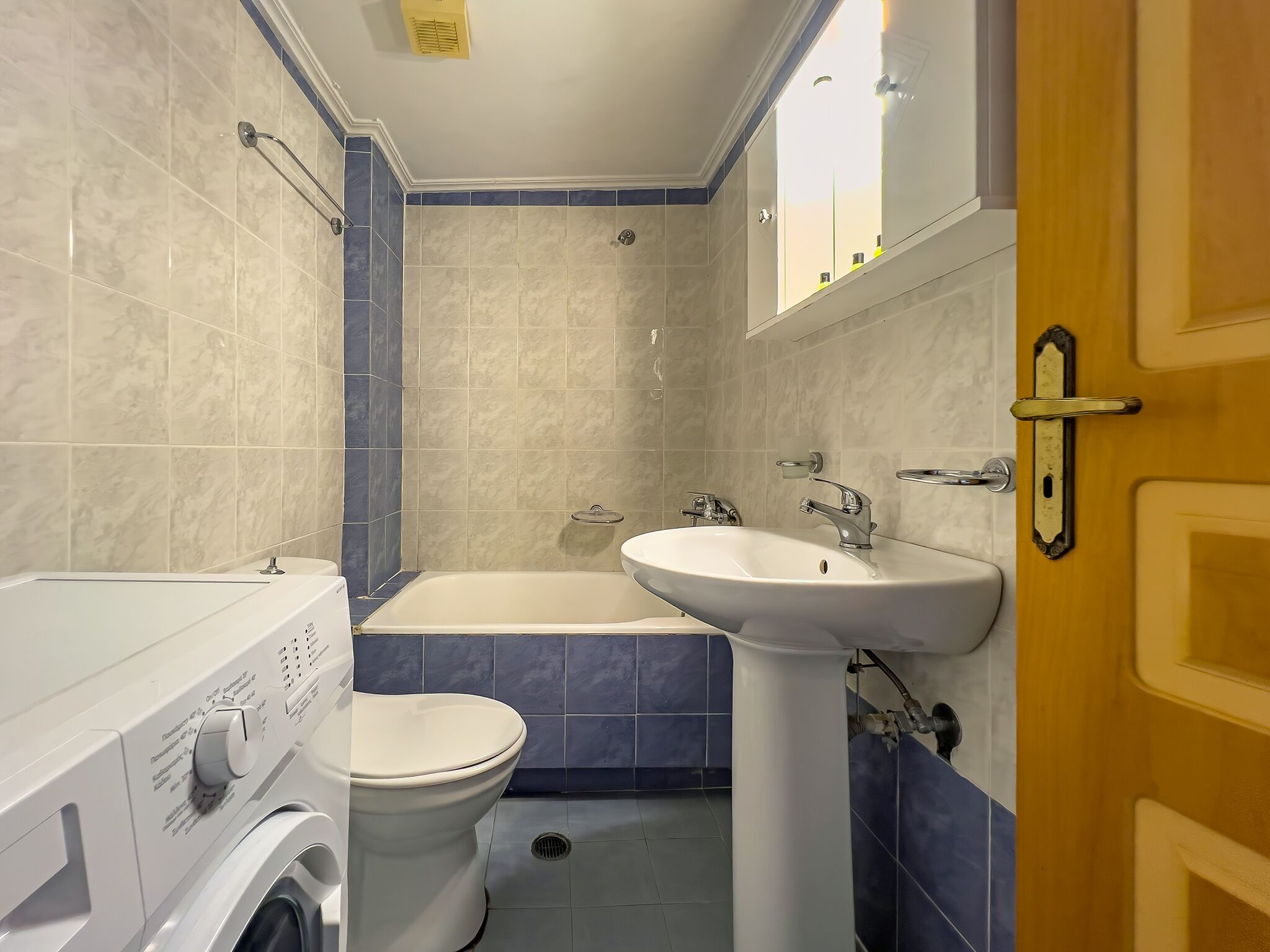 A bathroom with a bathtub, sink, toilet, and washing machine.