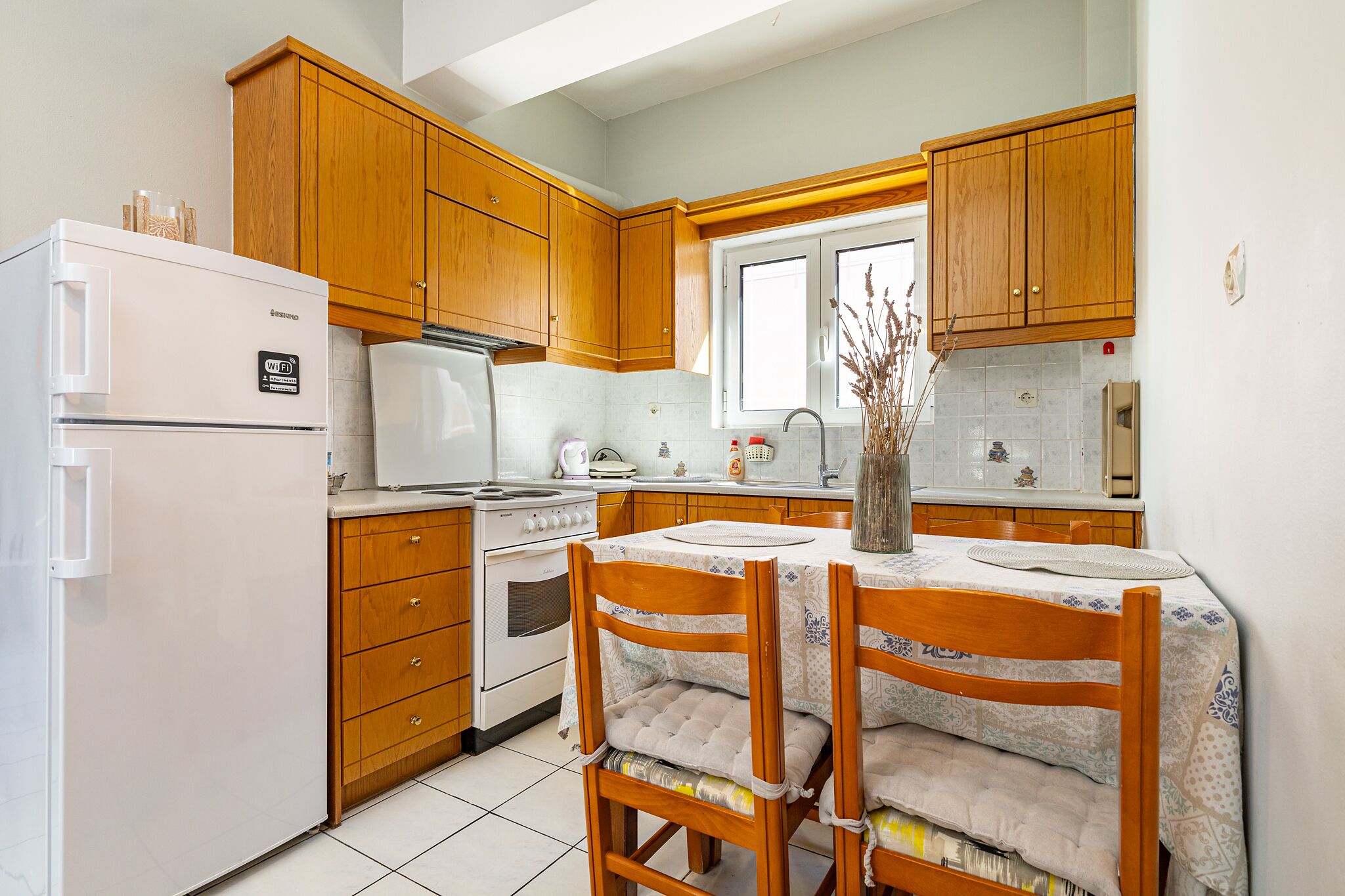 Una cocina con armarios de madera, un refrigerador blanco, una estufa y una mesa de comedor con sillas.