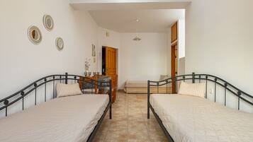 A bedroom with two beds, a desk, and a chair.