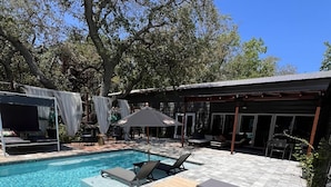 A pool area with lounge chairs and a pergola.