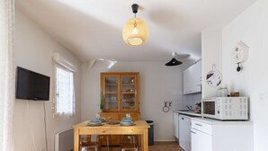 Eine kleine Küche mit einem Holztisch und -hocker, einer Mikrowelle und einem Schrank.