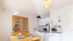Eine moderne Küche mit weißen Schränken, einem Holzespeisetisch und klaren Kunststoffhocker.