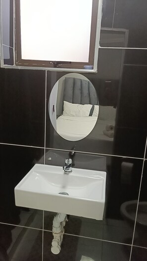 Ein Badezimmer mit einem weißen Waschbecken, einem Spiegel und einer Toilette.