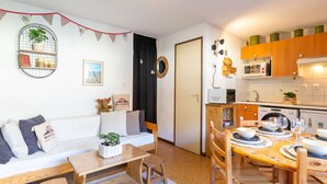 A compact living space with a kitchenette, a dining area, and a sofa with cushions. - Apartment for 6 in Vielle-Aure - Near cable car, private parking (Vielle-Aure)