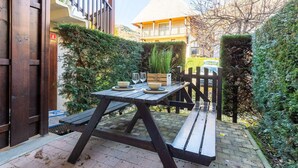 An outdoor patio with a wooden table and benches, surrounded by greenery and a fence. - Apartment for 6 in Vielle-Aure - Near cable car, private parking (Vielle-Aure)