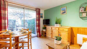 A cozy room with a dining table, chairs, a TV, and a window with curtains. - Apartment for 6 in Vielle-Aure - Near cable car, private parking (Vielle-Aure)