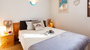 A neatly arranged bedroom with a bed, bedside tables, a wall-mounted light, a framed poster, and a heart-shaped decoration. - Apartment for 6 in Vielle-Aure - Near cable car, private parking (Vielle-Aure)