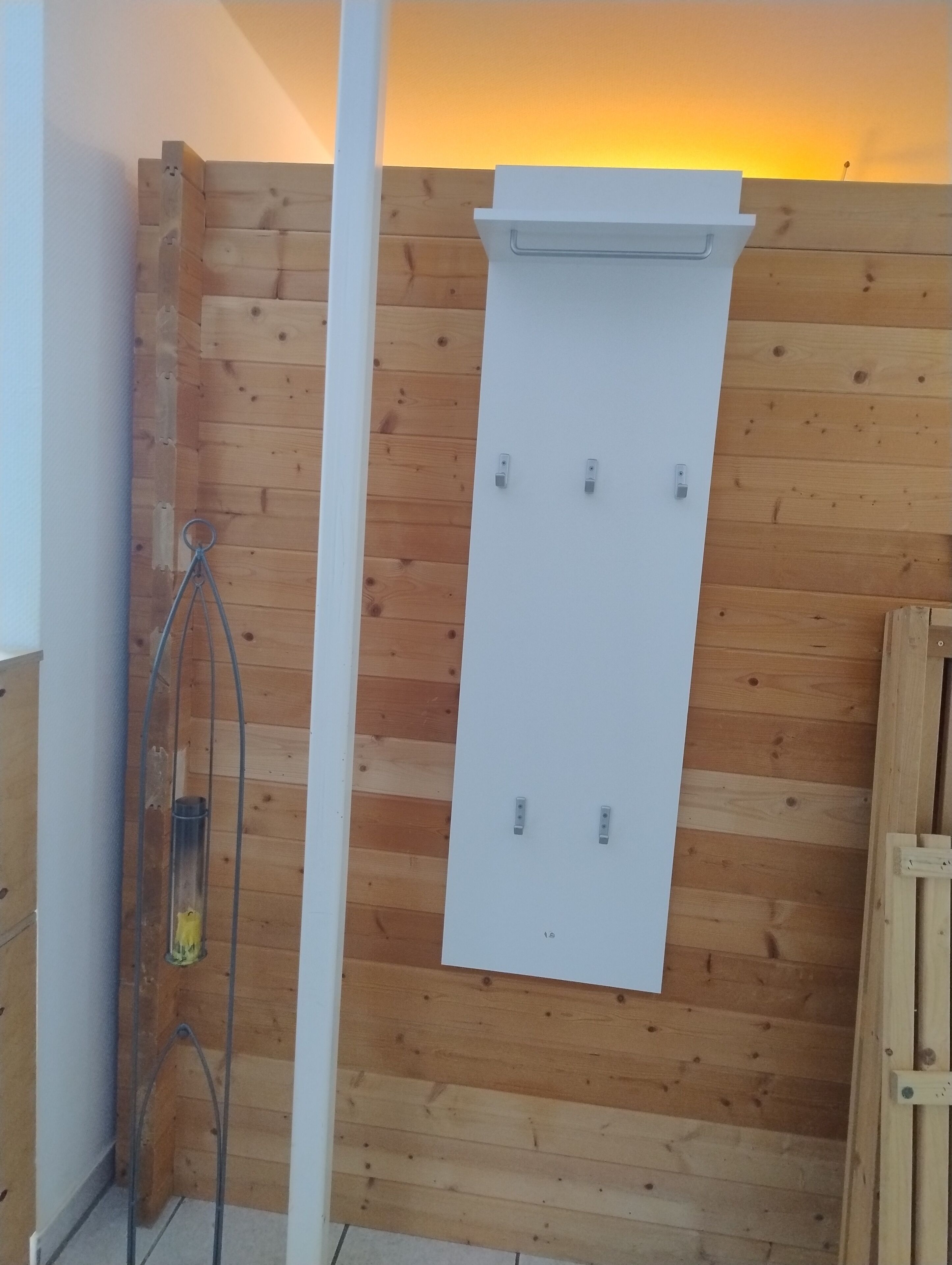 A wooden wall with a white panel, a metal shower, and a wooden door.