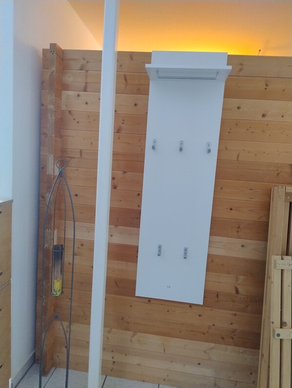 Pared de madera con un panel blanco, una ducha de metal y una puerta de madera.