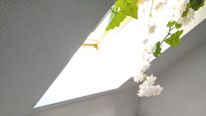Une baignoire remplie d’eau, une pomme de douche et une fenêtre donnant sur un paysage verdoyant.