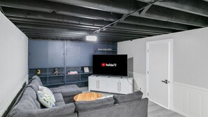 A modern living room with a grey sectional sofa, a wooden coffee table, and a flat-screen TV displaying YouTubeTV. - Bright & Roomy 5BR – Family-Ready Near Naval Base! (Libertyville)