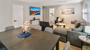 A modern living room with a dining area, featuring a dark wooden table, grey sofas, and a ceiling fan. - Bright & Roomy 5BR – Family-Ready Near Naval Base! (Libertyville)