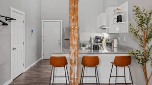 Eine moderne Küche mit einer zentralen Kochinsel, Barhocker und einem Blumentopf.
