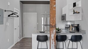 A modern kitchen with a central island, bar stools, and a wooden accent column. - Oregon District I Spacious I Free Parking (Dayton)