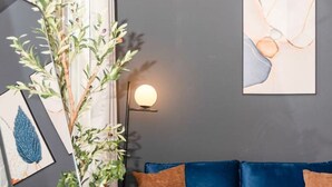 A modern living room with a blue velvet sofa, a floor lamp, and a mirror reflecting the room. - Oregon District I Spacious I Free Parking (Dayton)