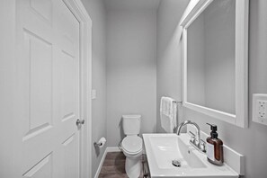 Une petite salle de bain propre, équipée de toilettes, d’un lavabo et d’un miroir.