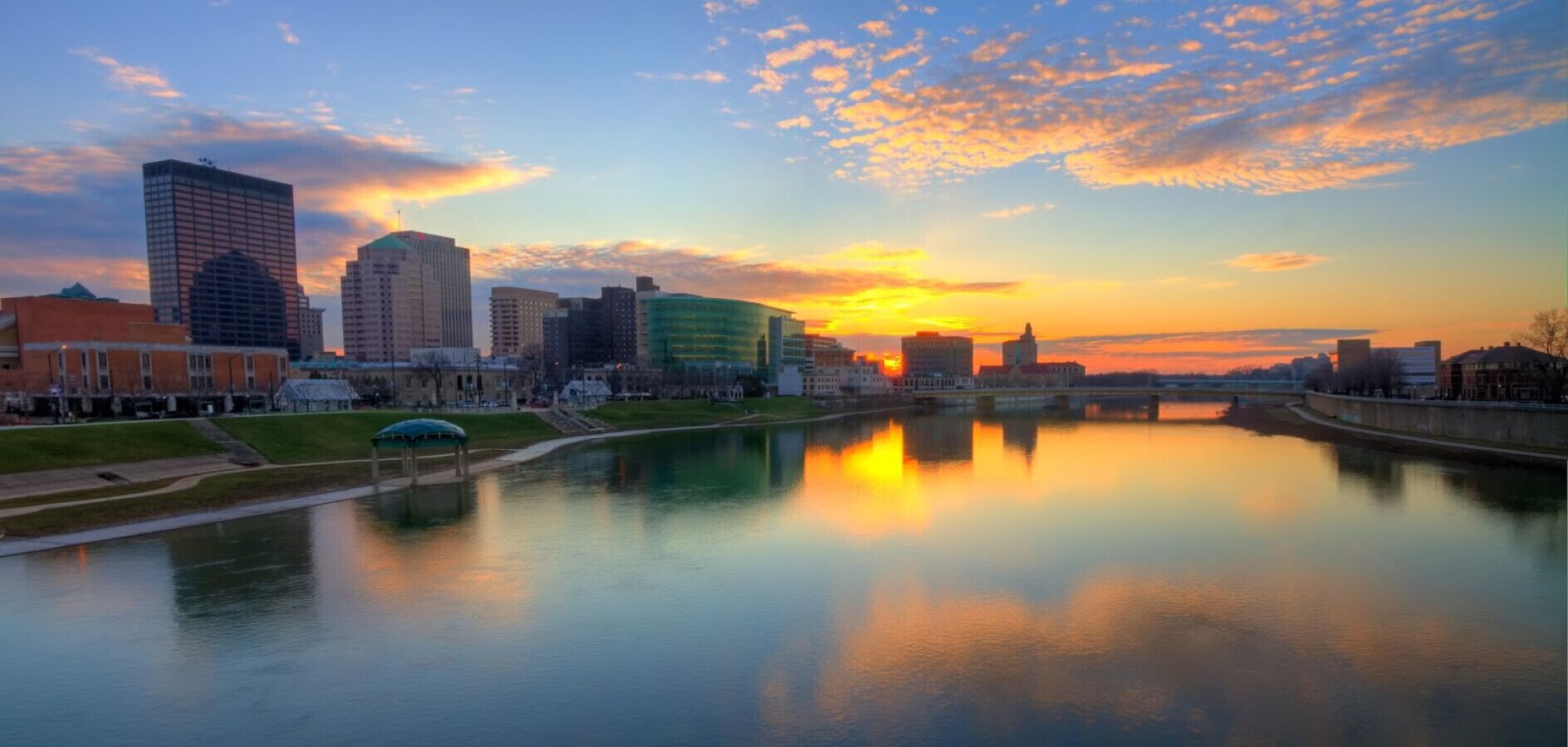 Un paisaje urbano con un río que refleja edificios y un atardecer.