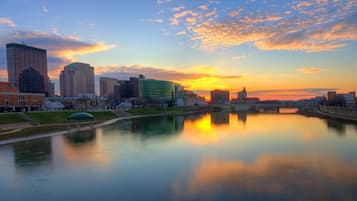 Un paisaje urbano con un río que refleja edificios y un atardecer.