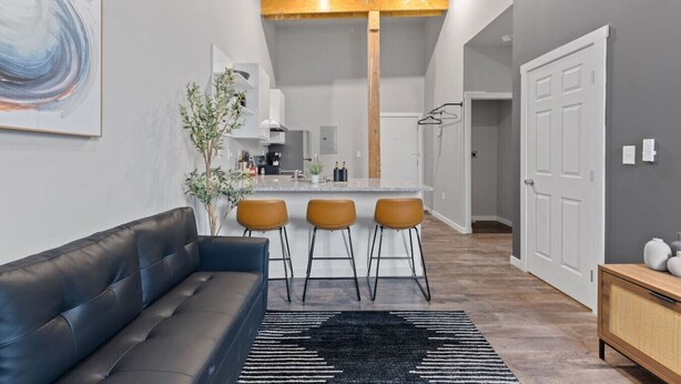 Una cocina moderna con una isla central, taburetes de bar y un comedor.