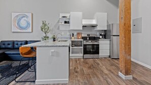 Una cocina moderna con armarios blancos, un horno de acero inoxidable y una isla integrada con un lavamanos.