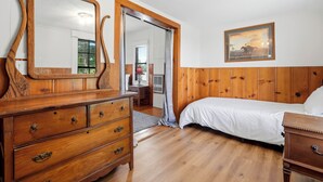 A bedroom with a wooden dresser, a bed, and a painting on the wall. - Tenkiller Pine Cabin Escape Near Lake Adventures A (Cookson)