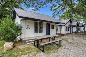 A small building with a metal roof, a wooden door, and a bench in front.