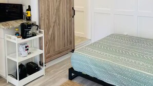 Una camera da letto con un letto, una ventola a soffitto, un armadio e un mobile contenitore bianco.