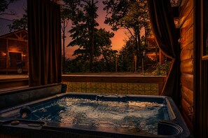 A hot tub with a view of a wooden cabin and trees. - Gatlinburg Retreat:  Hot Tub, Game Room & Pool (Gatlinburg)