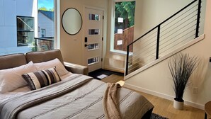Een slaapkamer met een bed, een groot raam, een trap en een potplant.