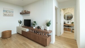 A modern living room with a wooden reception desk, a flat-screen TV, and decorative plants.
