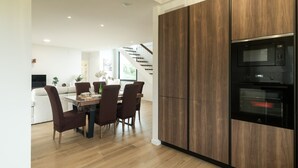A modern kitchen with dark wood cabinets, a built-in oven, and a dining area with a wooden table and chairs.