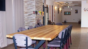 A long wooden table with six chairs, a tiled floor, and a modern interior with a brick accent wall and wall-mounted lights. - Dar naima  (Essaouira)