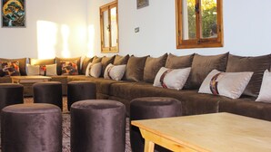 A cozy living room with a brown sofa set, a wooden coffee table, and a patterned rug. - Dar naima  (Essaouira)