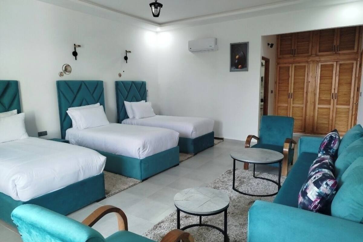A hotel room with two beds, a sofa, a small table, and a wardrobe.