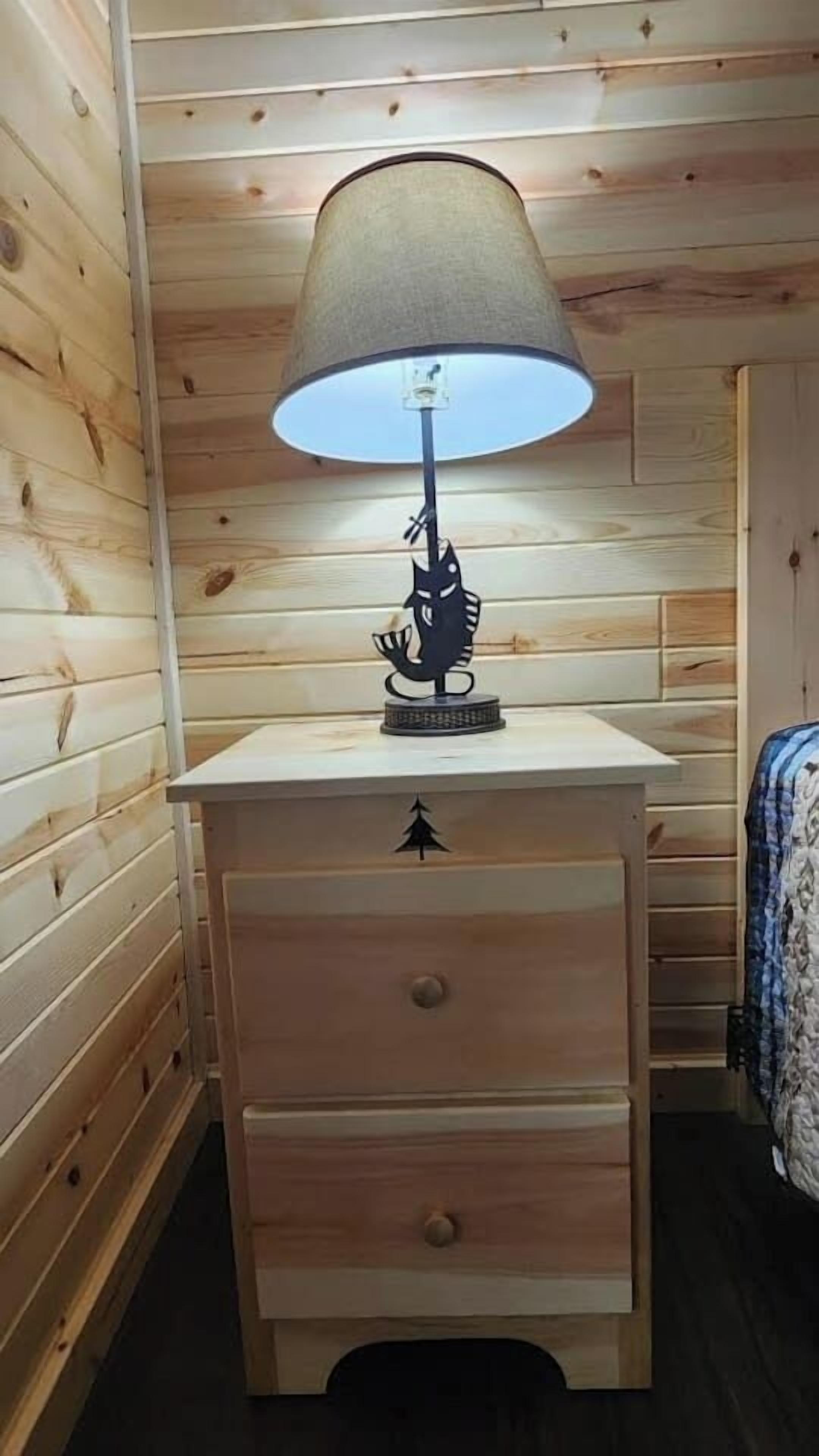 Een houten nachtkastje met een lamp en een lade.