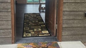 Eingang eines Holzchalets mit Fußmatte und Blick ins Freie.