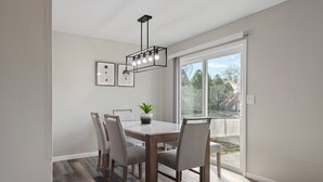 A dining area with a wooden table, four chairs, a potted plant, and a modern light fixture. - Modern 5BR Sleeps 12 Fire Pit 85" TV Decatur (Decatur)