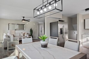 A modern kitchen with a built-in refrigerator, a dining area with a marble table, and a ceiling fan. - Modern 5BR Sleeps 12 Fire Pit 85" TV Decatur (Decatur)