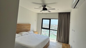A modern bedroom with a large bed, a ceiling fan, an air conditioning unit, and a view of a marina through a large window. - Sea and Sand (Progreso)