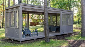 Un espace extérieur abrité, avec une table et des chaises, entouré d’arbres.