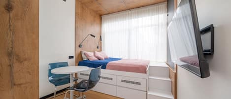 A compact bedroom with a bed, a desk, and a chair.