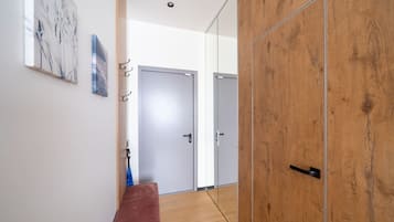 A hallway with a wooden bench, a door, and a wall-mounted artwork.