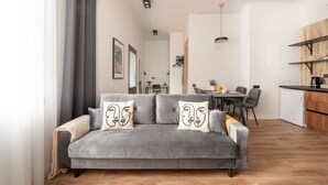 En moderne stue med en grå sofa, et spiseområde og et køkken.