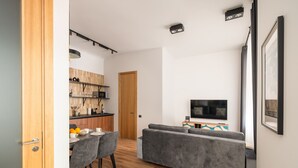 En moderne stue med en grå sofa, et fladskærms-tv og et træspisebord med stole.